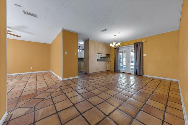 unfurnished living room with french doors, ceiling fan with notable chandelier, and dark tile patterned floors