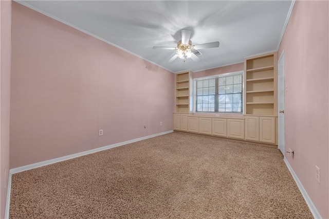 unfurnished room featuring carpet flooring, ceiling fan, ornamental molding, and built in shelves