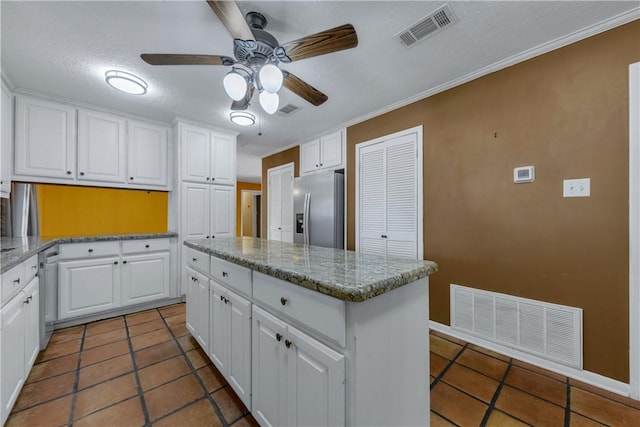 kitchen with white cabinets, a kitchen island, ornamental molding, and stainless steel appliances