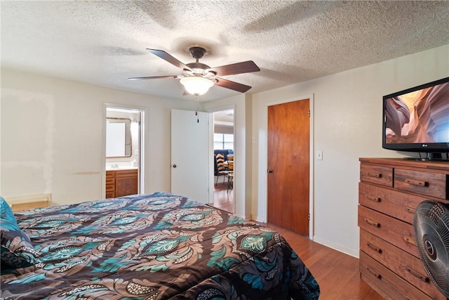 10072 Riley Green Rd, Franklin, TX 77856 - bedroom with wood finished floors, ceiling fan, connected bathroom, and a textured ceiling