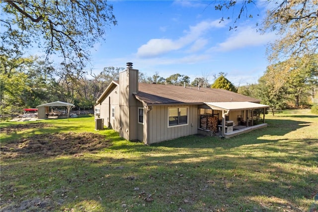 rear view of property featuring a carport and a yard