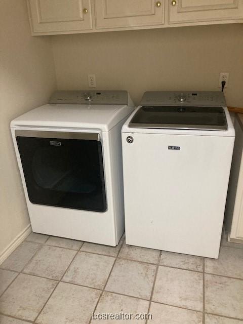 washroom with cabinets, light tile patterned floors, and washing machine and dryer