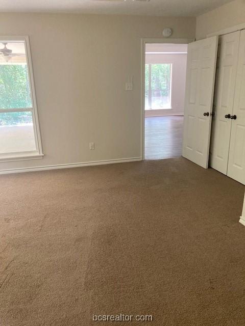 unfurnished room featuring a wealth of natural light and dark carpet