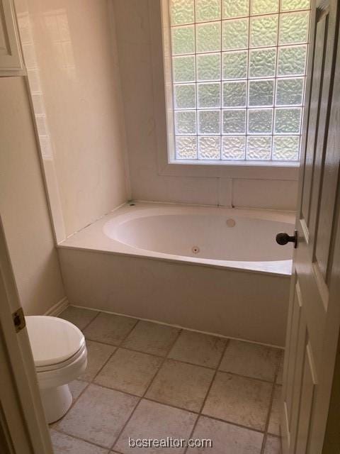 bathroom featuring a washtub, tile patterned floors, and toilet