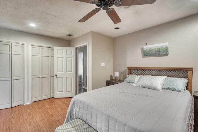 bedroom with multiple closets, ceiling fan, and light wood-type flooring