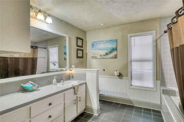 full bathroom with toilet, a textured ceiling, vanity, a healthy amount of sunlight, and tile patterned flooring