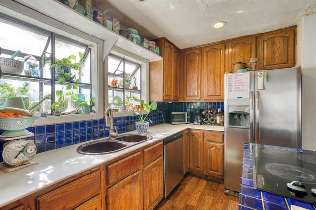 kitchen featuring sink, dark hardwood / wood-style flooring, decorative backsplash, stainless steel appliances, and a textured ceiling