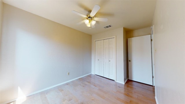 unfurnished bedroom featuring ceiling fan, light hardwood / wood-style floors, and a closet