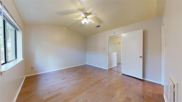 empty room with ceiling fan, lofted ceiling with beams, and light hardwood / wood-style flooring