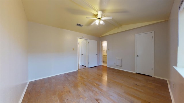 unfurnished bedroom with connected bathroom, vaulted ceiling with beams, ceiling fan, and light wood-type flooring