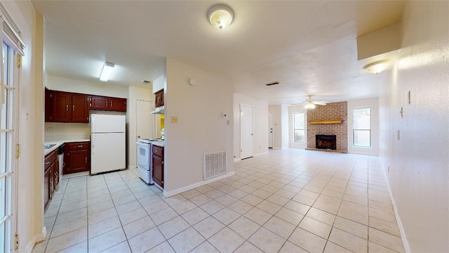 kitchen featuring light tile patterned floors, white appliances, a brick fireplace, and ceiling fan