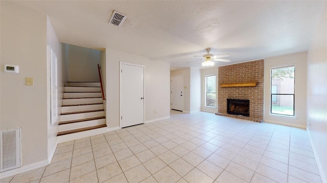 unfurnished living room with plenty of natural light, light tile patterned floors, a textured ceiling, and ceiling fan