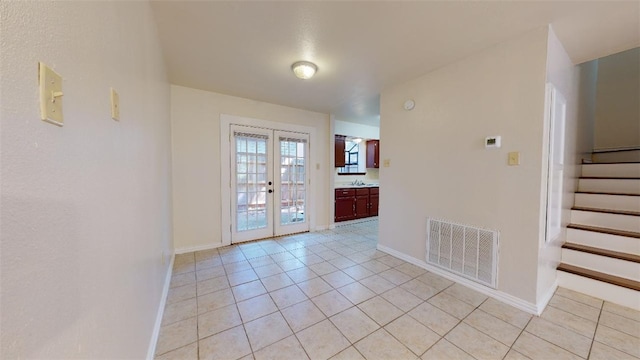 empty room with sink, french doors, and light tile patterned flooring