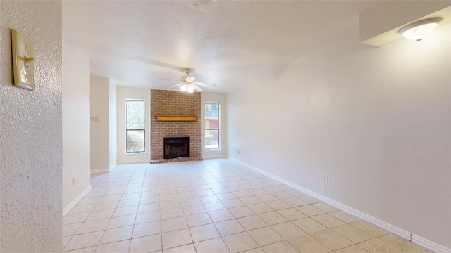 unfurnished living room featuring ceiling fan, a brick fireplace, and light tile patterned floors