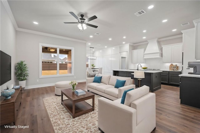 living room featuring ceiling fan, sink, crown molding, and light wood-type flooring