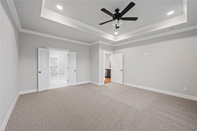 unfurnished bedroom with light carpet, ceiling fan, crown molding, and a raised ceiling