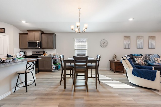 dining area with light hardwood / wood-style floors and an inviting chandelier