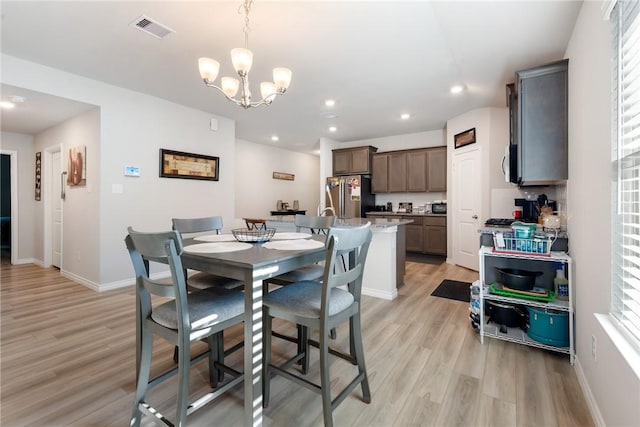 dining room featuring light wood-type flooring and an inviting chandelier