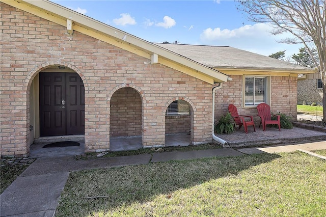 entrance to property with a patio and a lawn