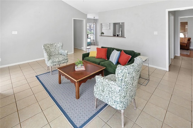 living area with light tile patterned floors, baseboards, and vaulted ceiling