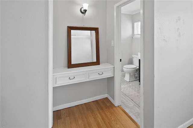 bathroom with toilet, wood finished floors, and baseboards