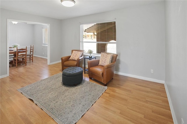 sitting room with baseboards and light wood-style flooring