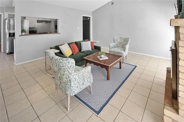 living area featuring baseboards, visible vents, light tile patterned flooring, a fireplace with raised hearth, and vaulted ceiling