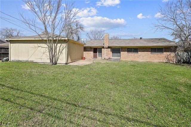 back of property with brick siding, fence, a lawn, a chimney, and an outbuilding