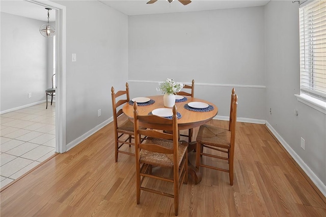 dining area with a ceiling fan, light wood-type flooring, and baseboards