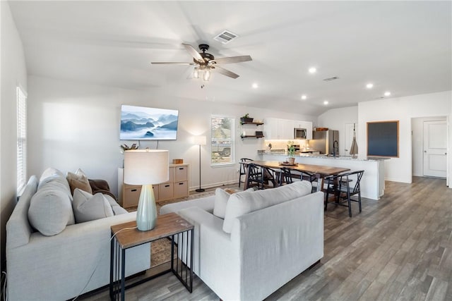 living room featuring hardwood / wood-style flooring, vaulted ceiling, and ceiling fan