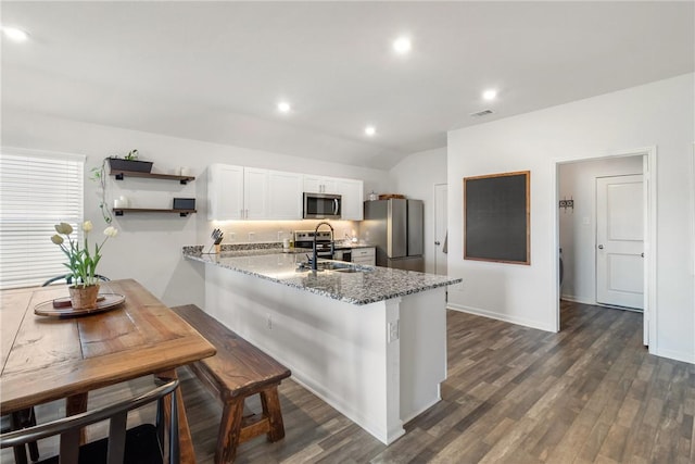 kitchen featuring white cabinetry, a kitchen breakfast bar, stainless steel appliances, stone countertops, and kitchen peninsula