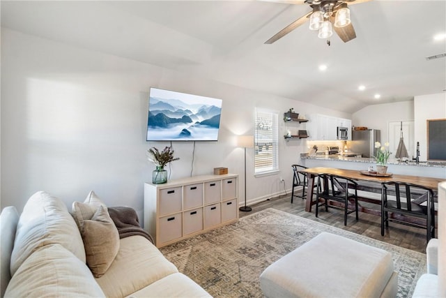 living room featuring vaulted ceiling, ceiling fan, and light wood-type flooring