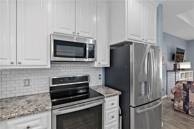 kitchen with light stone countertops, appliances with stainless steel finishes, light wood-type flooring, and white cabinetry