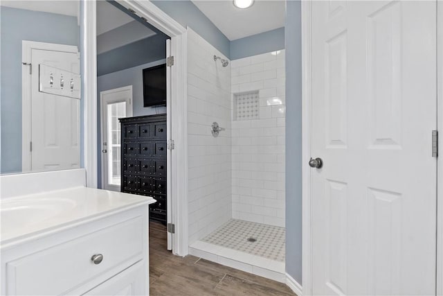 bathroom with hardwood / wood-style floors, vanity, and tiled shower