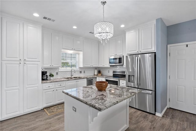 kitchen with sink, a center island, decorative light fixtures, white cabinets, and appliances with stainless steel finishes