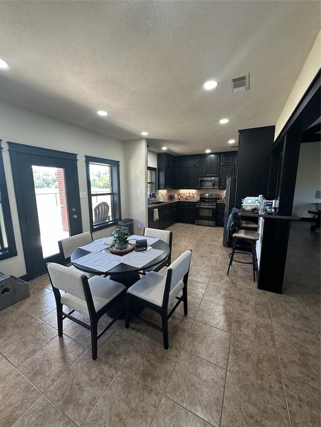 tiled dining area with a textured ceiling and sink