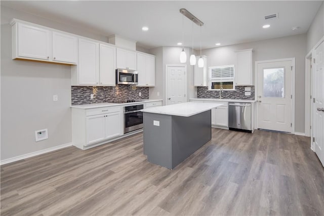 kitchen featuring pendant lighting, a center island, white cabinetry, and appliances with stainless steel finishes