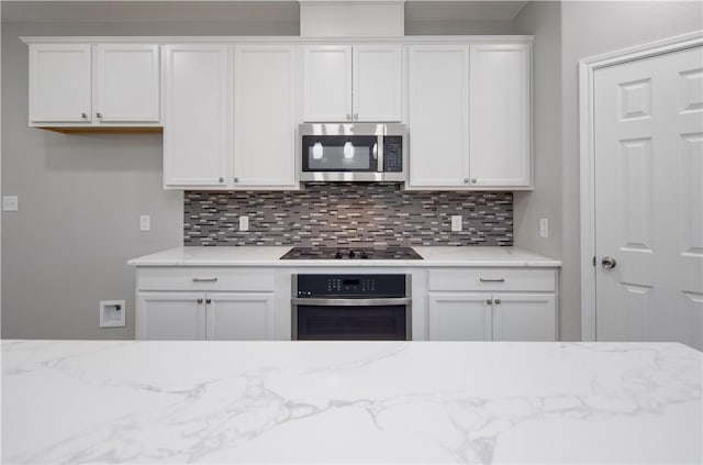 507 Brosig Ave, Navasota, TX 77868 - kitchen featuring stainless steel appliances, decorative backsplash, white cabinets, and light stone countertops