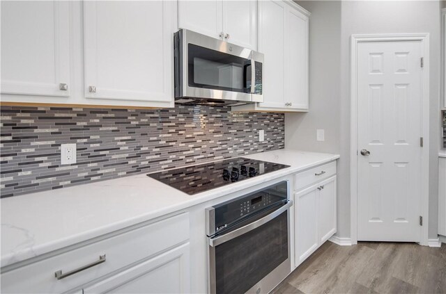 507 Brosig Ave, Navasota, TX 77868 - kitchen with stainless steel appliances, light wood finished floors, tasteful backsplash, and white cabinets