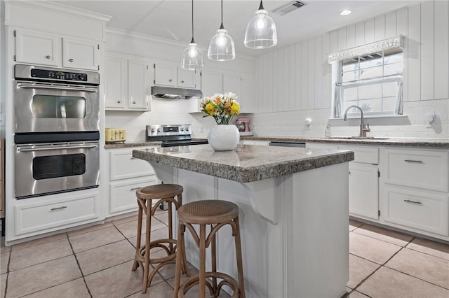 kitchen featuring stainless steel appliances, a kitchen island, and white cabinets