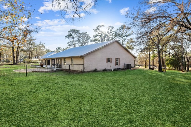 view of property exterior featuring central air condition unit and a lawn