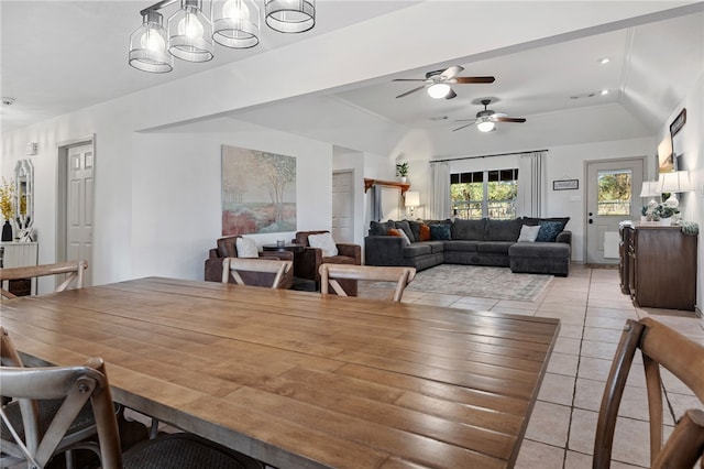 tiled dining space featuring ceiling fan with notable chandelier and vaulted ceiling