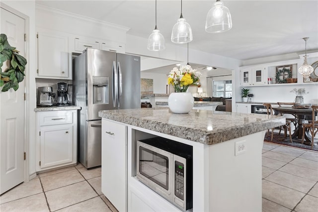 kitchen with stainless steel appliances, a kitchen island, pendant lighting, and white cabinets