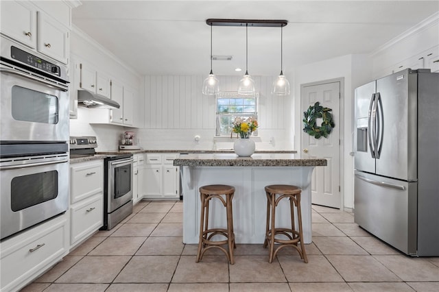 kitchen featuring stainless steel appliances, tasteful backsplash, white cabinets, a kitchen island, and decorative light fixtures