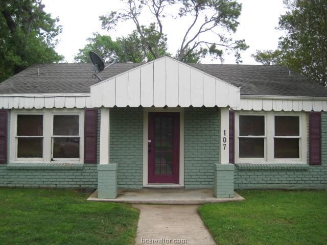 bungalow-style home featuring a shingled roof, a front yard, and brick siding