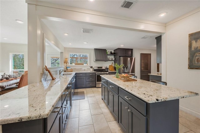 kitchen with visible vents, open shelves, a peninsula, a sink, and appliances with stainless steel finishes