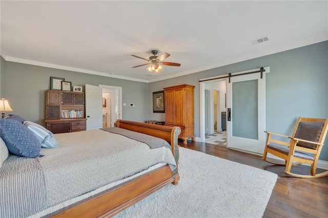 bedroom with dark wood-type flooring, a barn door, and ornamental molding