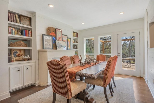 dining room featuring built in features, a healthy amount of sunlight, and dark wood-style flooring