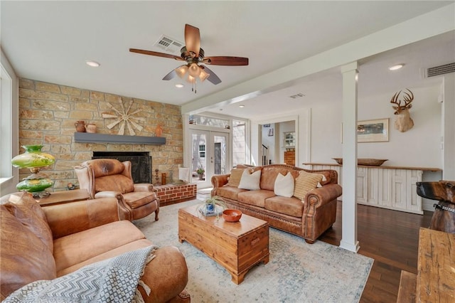 living area featuring a fireplace, wood finished floors, a ceiling fan, and visible vents