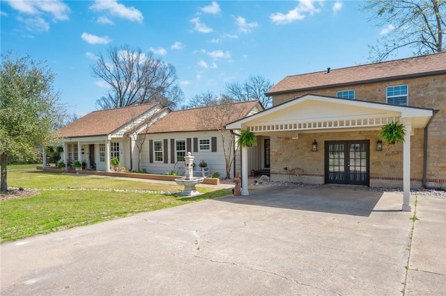 back of house with french doors, stone siding, a yard, and driveway